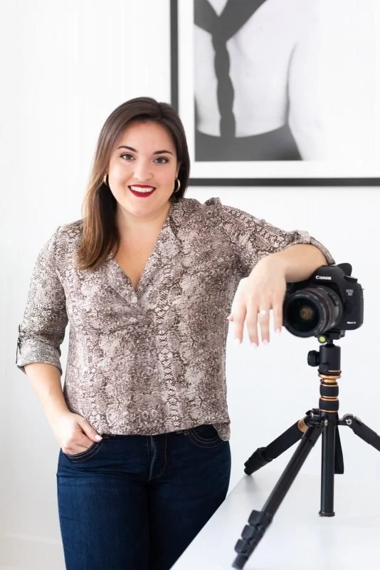 female freelancer leans on camera and desk at white wall studio woodstock atlanta