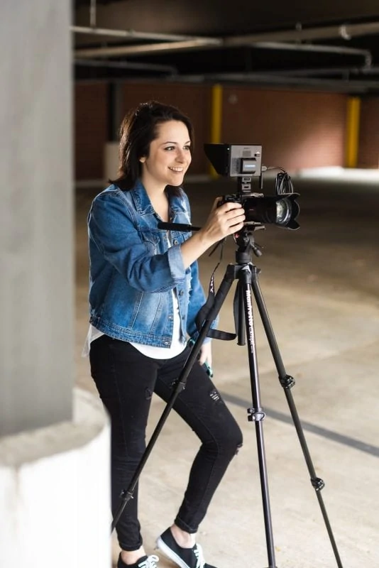 atlanta videographer smiles with camera on tripod