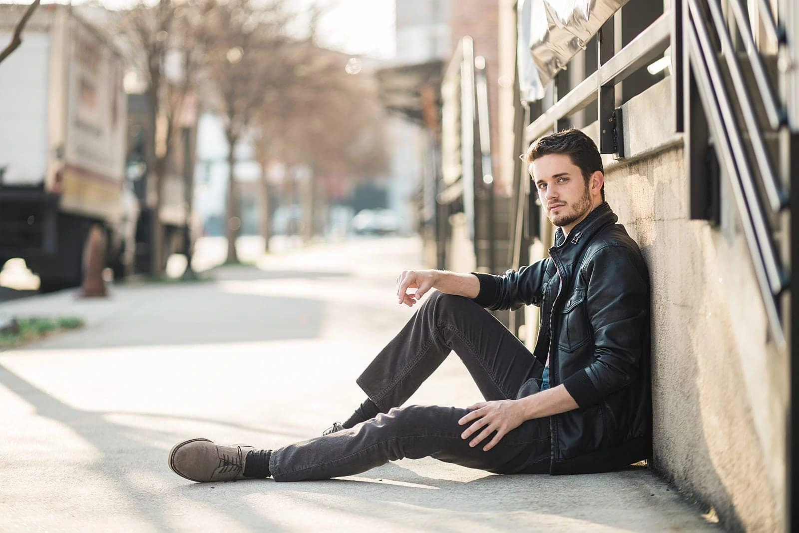 atlanta male actor in leather jacket sits on sidewalk of west midtown