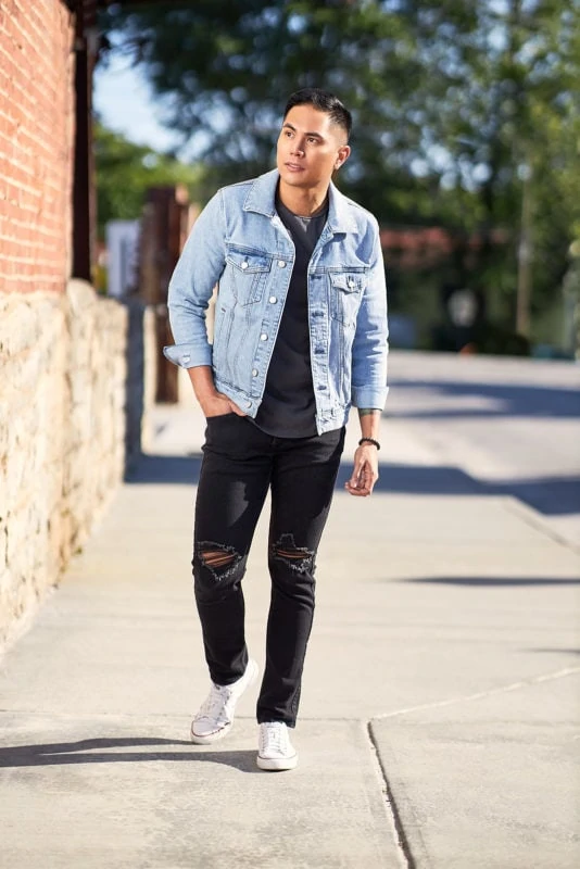 flash portrait of man in jean jacket walking on urban sidewalk in direct sunlight