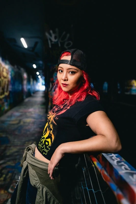 punk skater girl leaning on railing of graffiti tunnel portrait
