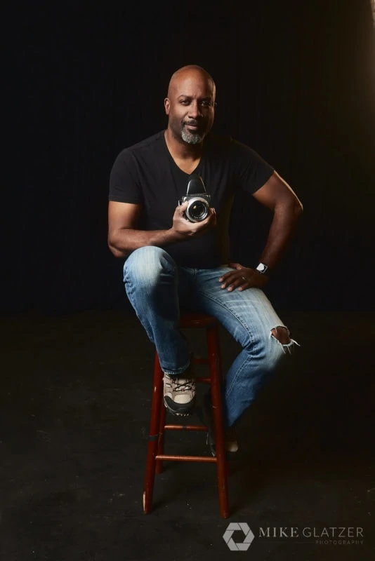 black photographer sits on stool