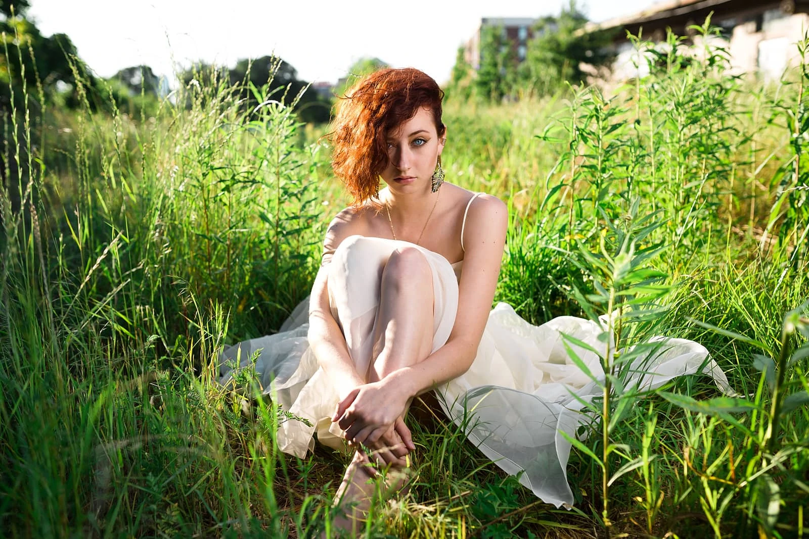 red head girl in white dress sits in greed field for atlanta portrait photography