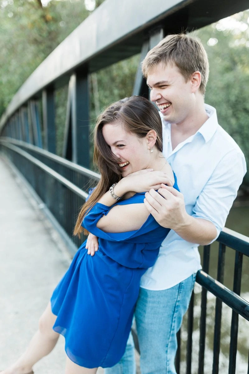 couple laughs on park bridge during engagement session in Roswell Atlanta