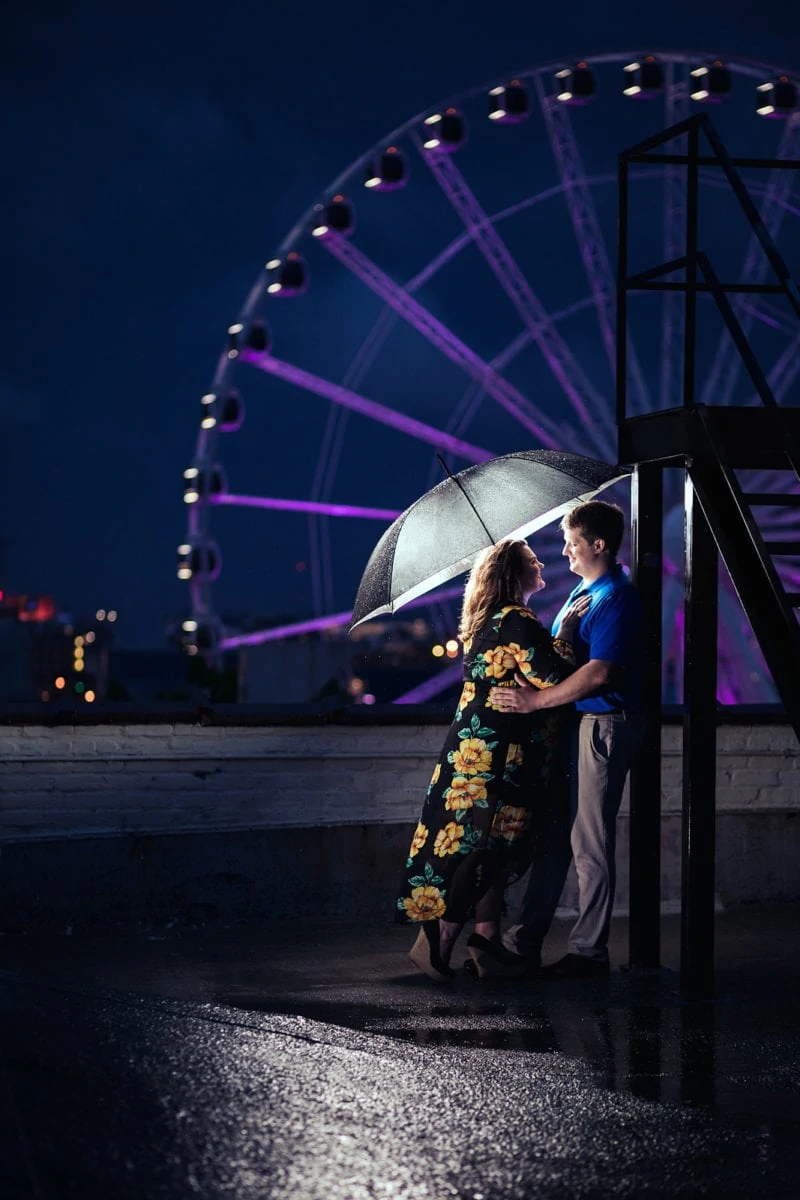 couple hugs in the rain with ferris wheel atlanta skyline