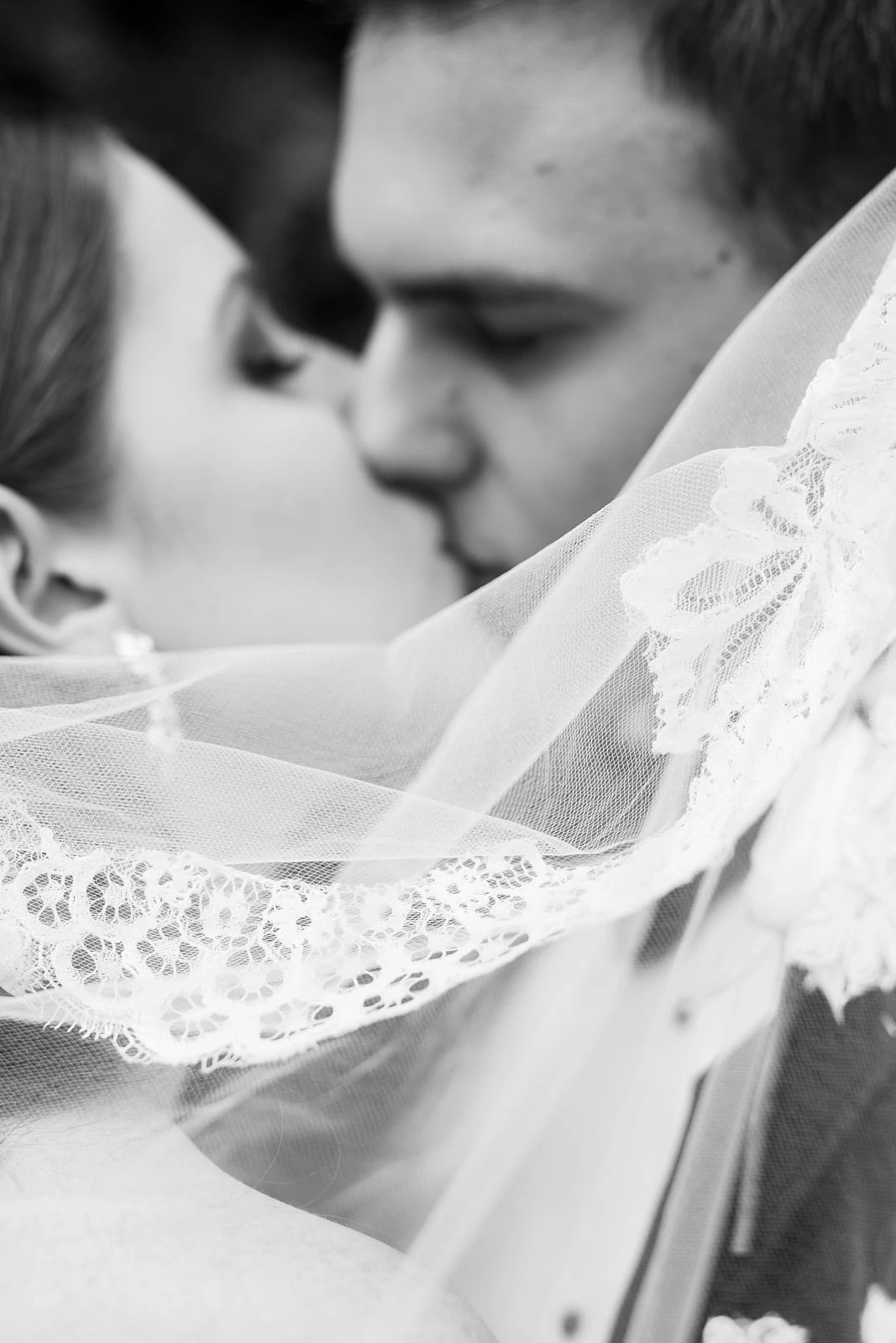 groom kisses bride behind wedding veil