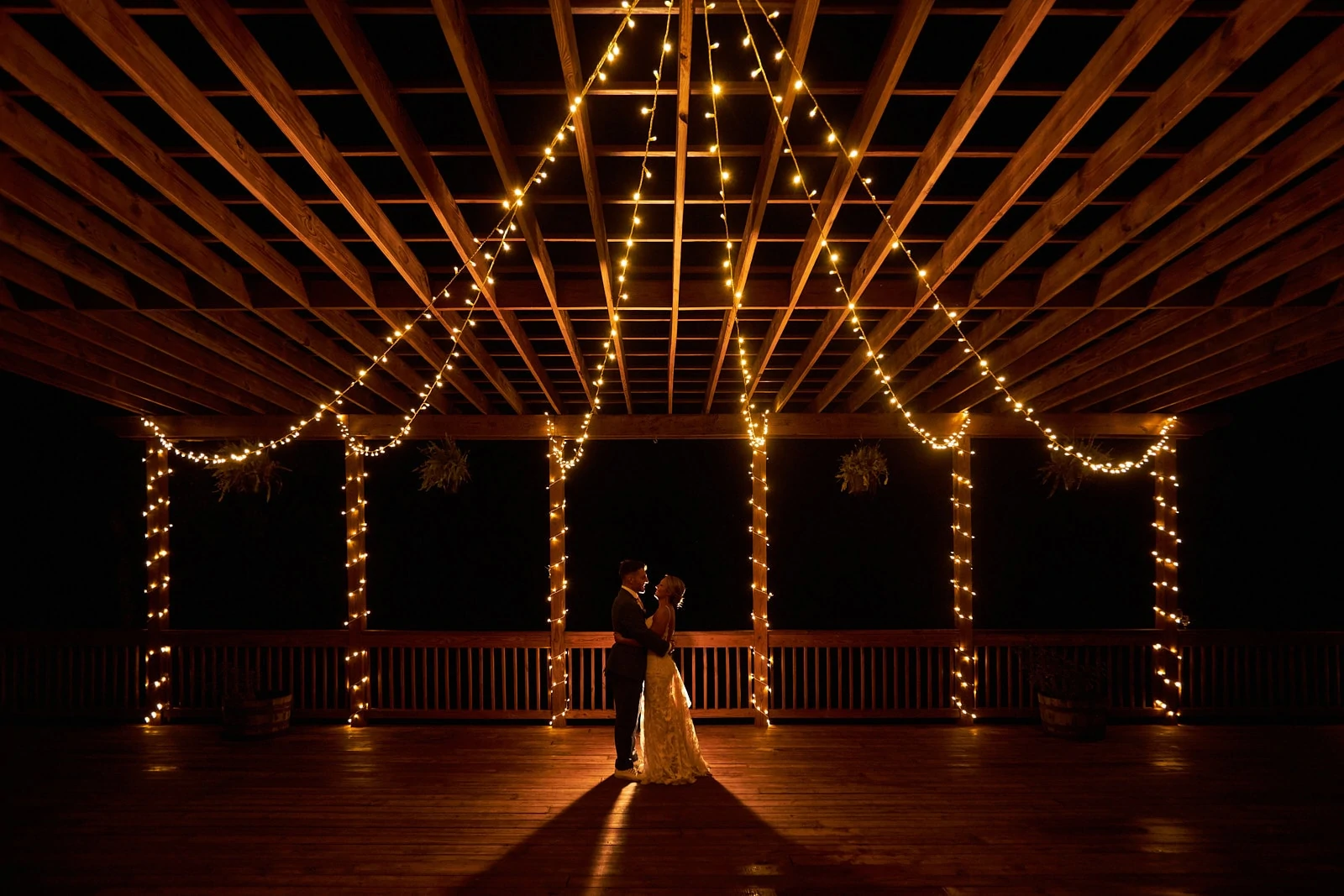 bride and groom kiss under string lights of willows farm